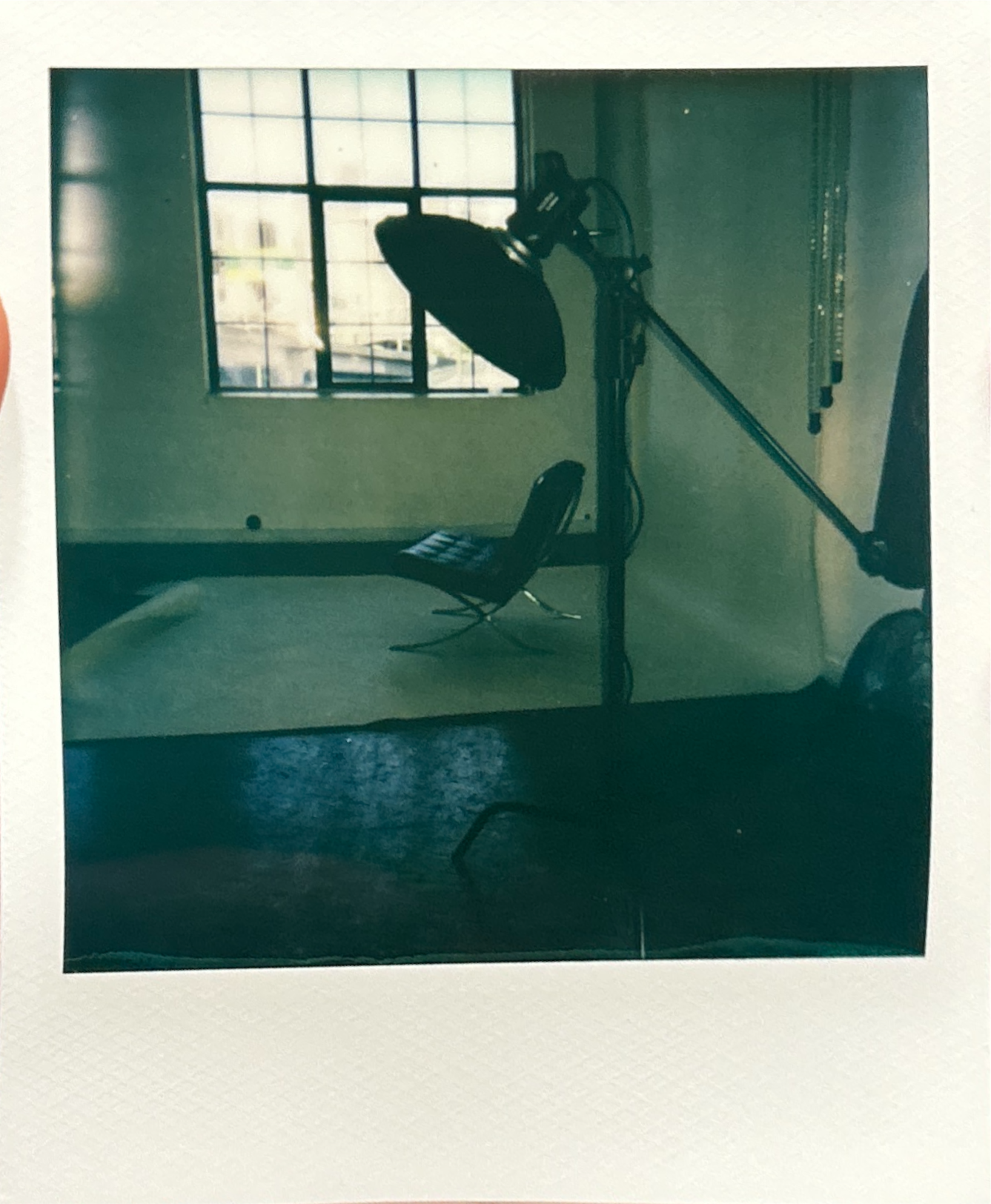 A photo studio with a spotlight, a chair, and a large window letting in natural light.